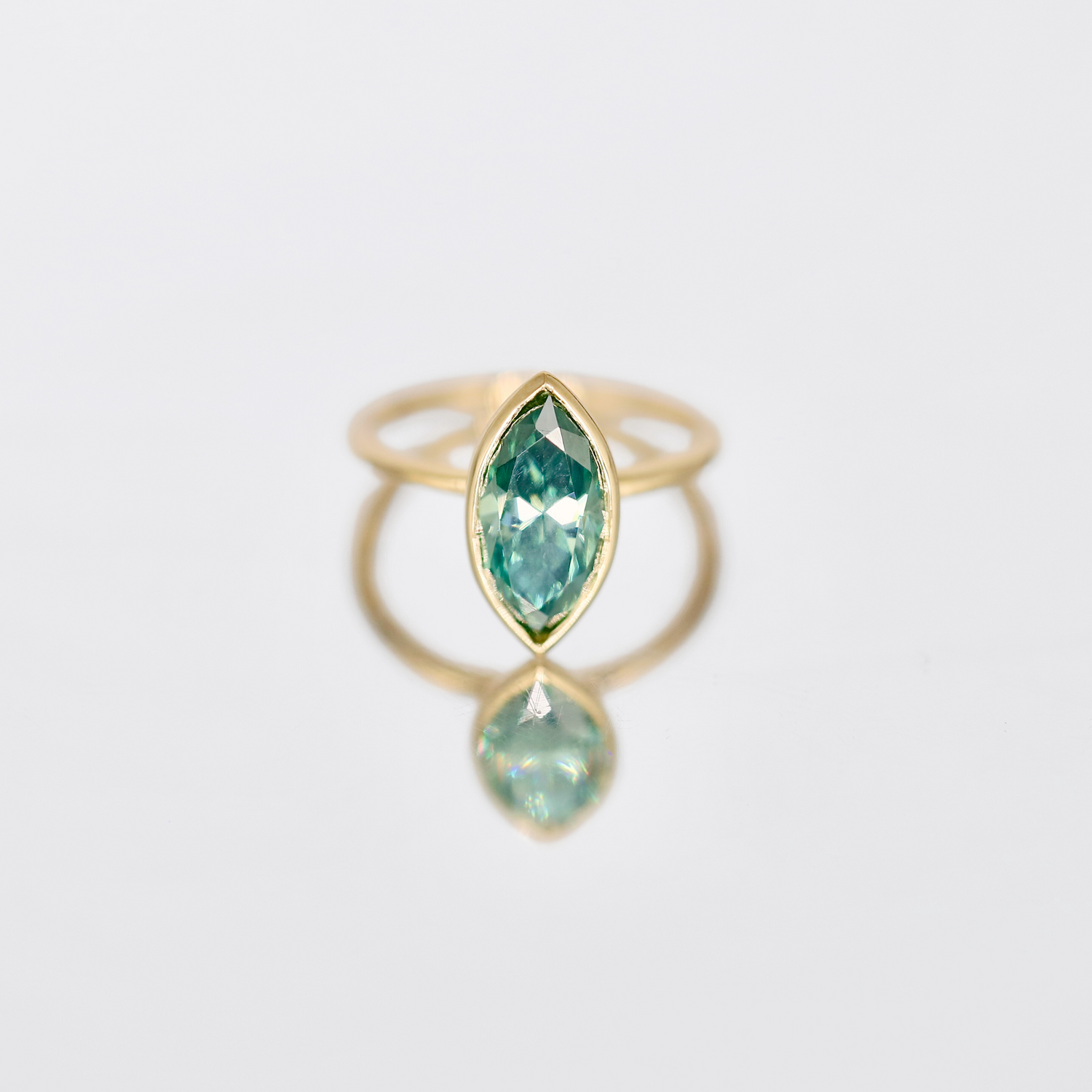 Zara | Bezel-Set Marquise Cut Blue-Green Moissanite Ring – Elegant marquise cut moissanite in a striking blue-green hue, set in a sleek bezel setting. Crafted in solid gold for a unique and timeless look.